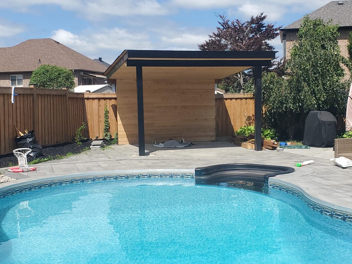 Wooden pergola with sturdy concrete footings in a snowy backyard