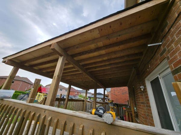 Roof installation in progress with workers and materials on site in spring